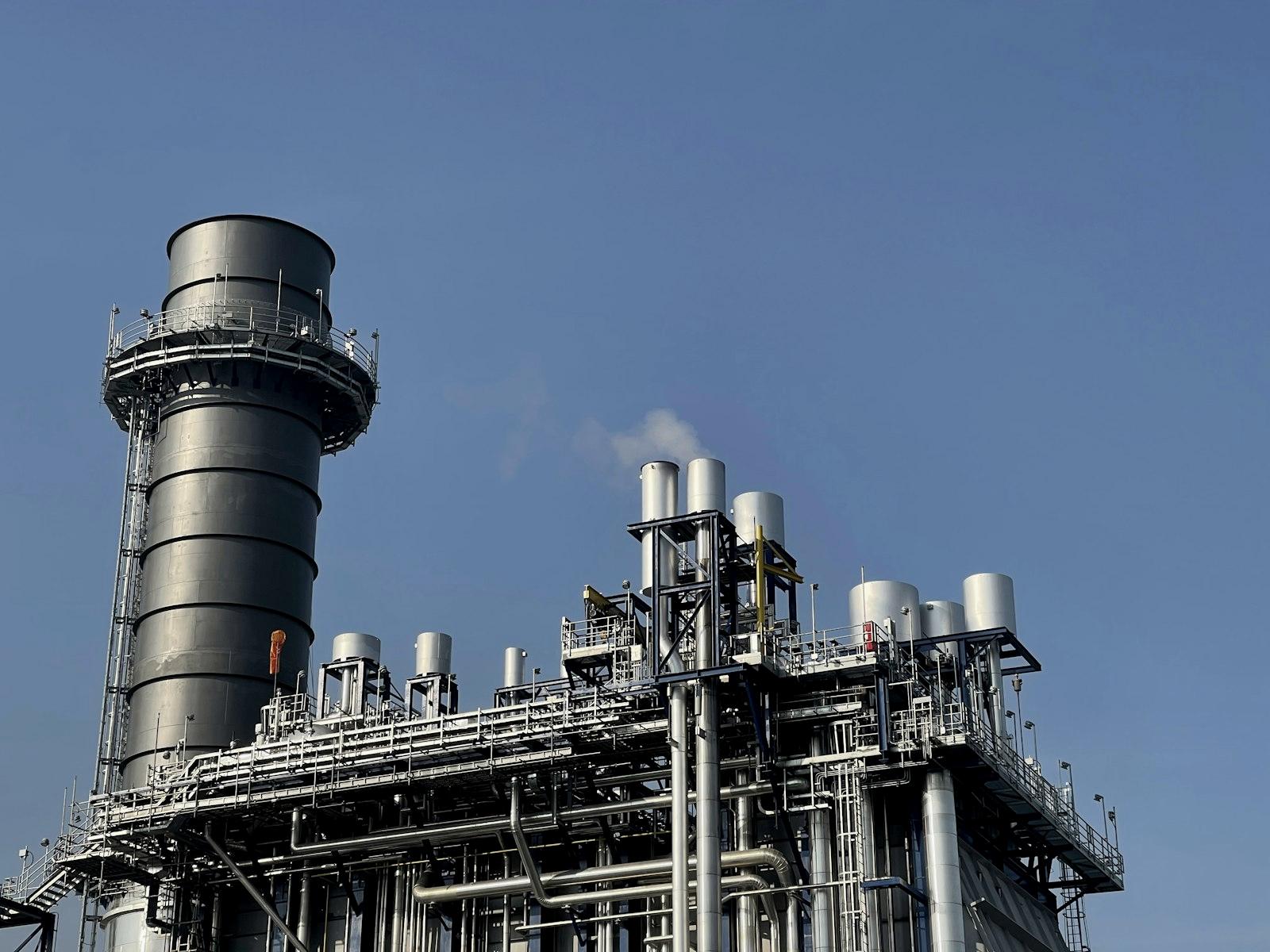 Gas processing facility with stack and pipework under a clear sky